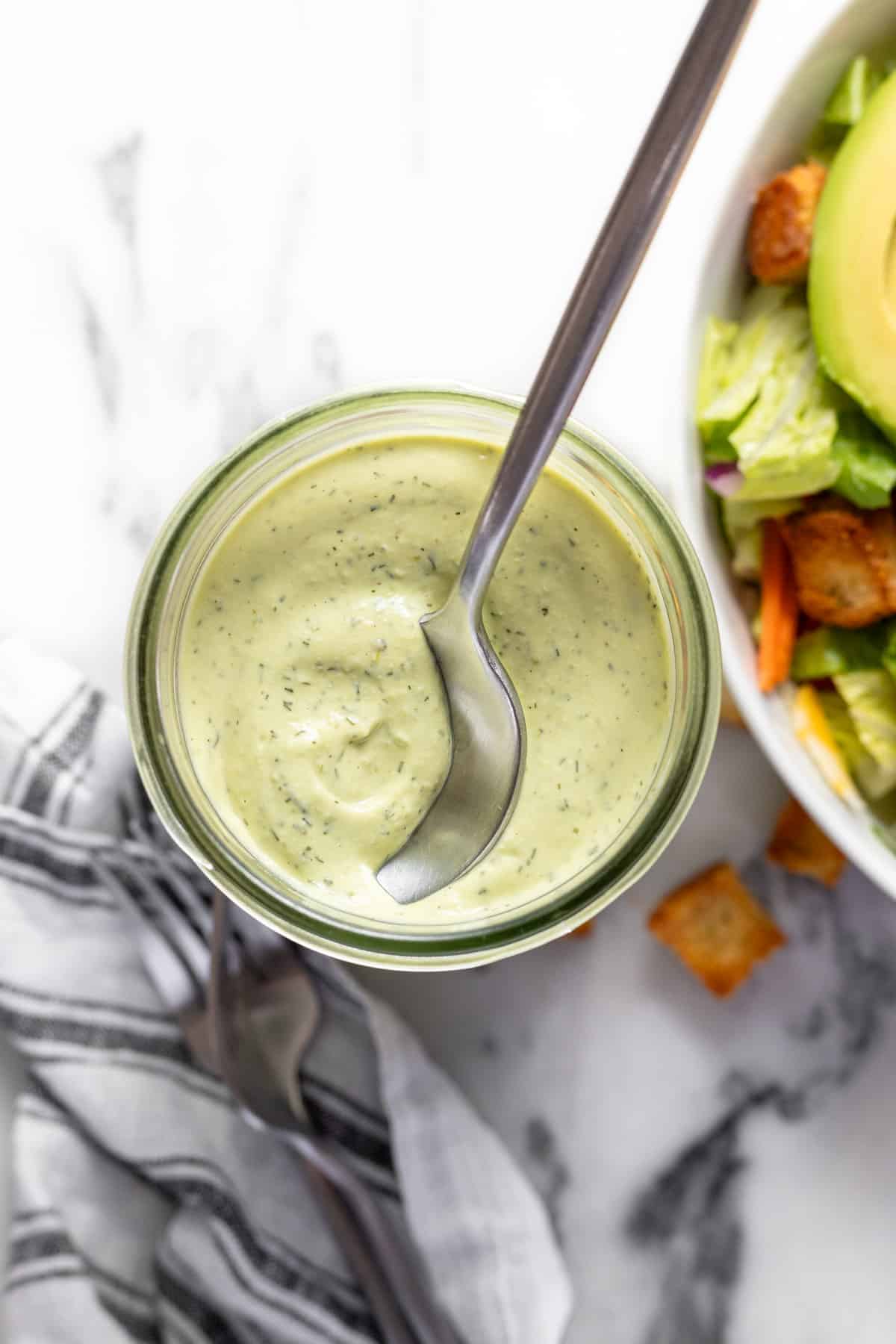 Wide-mouth mason jar filled with creamy homemade avocado lime ranch dressing. 