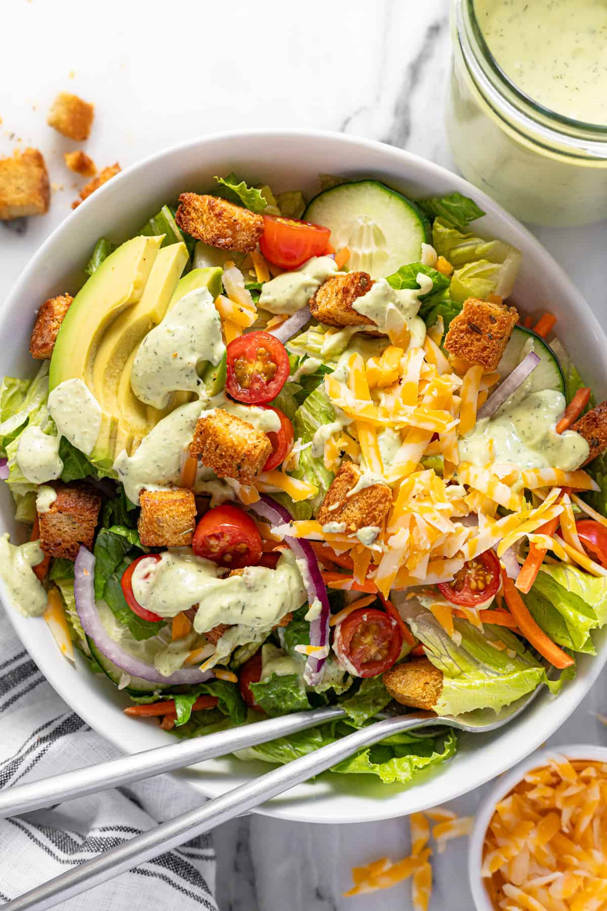 Large bowl filled with a house salad topped with creamy avocado lime ranch dressing.