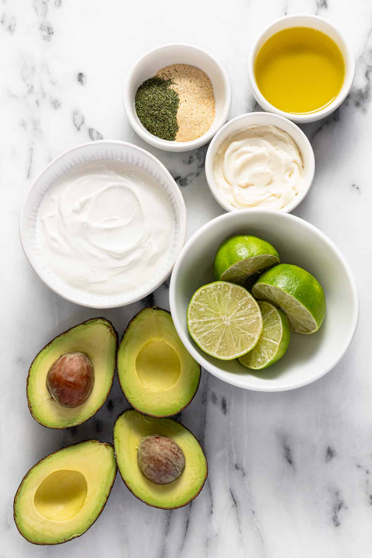 Bowls of ingredients to make creamy avocado salad dressing.