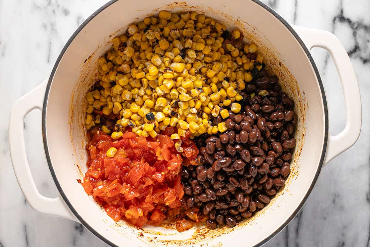 Large pot filled with sauteed veggies, roasted corn, diced tomatoes, and black beans.