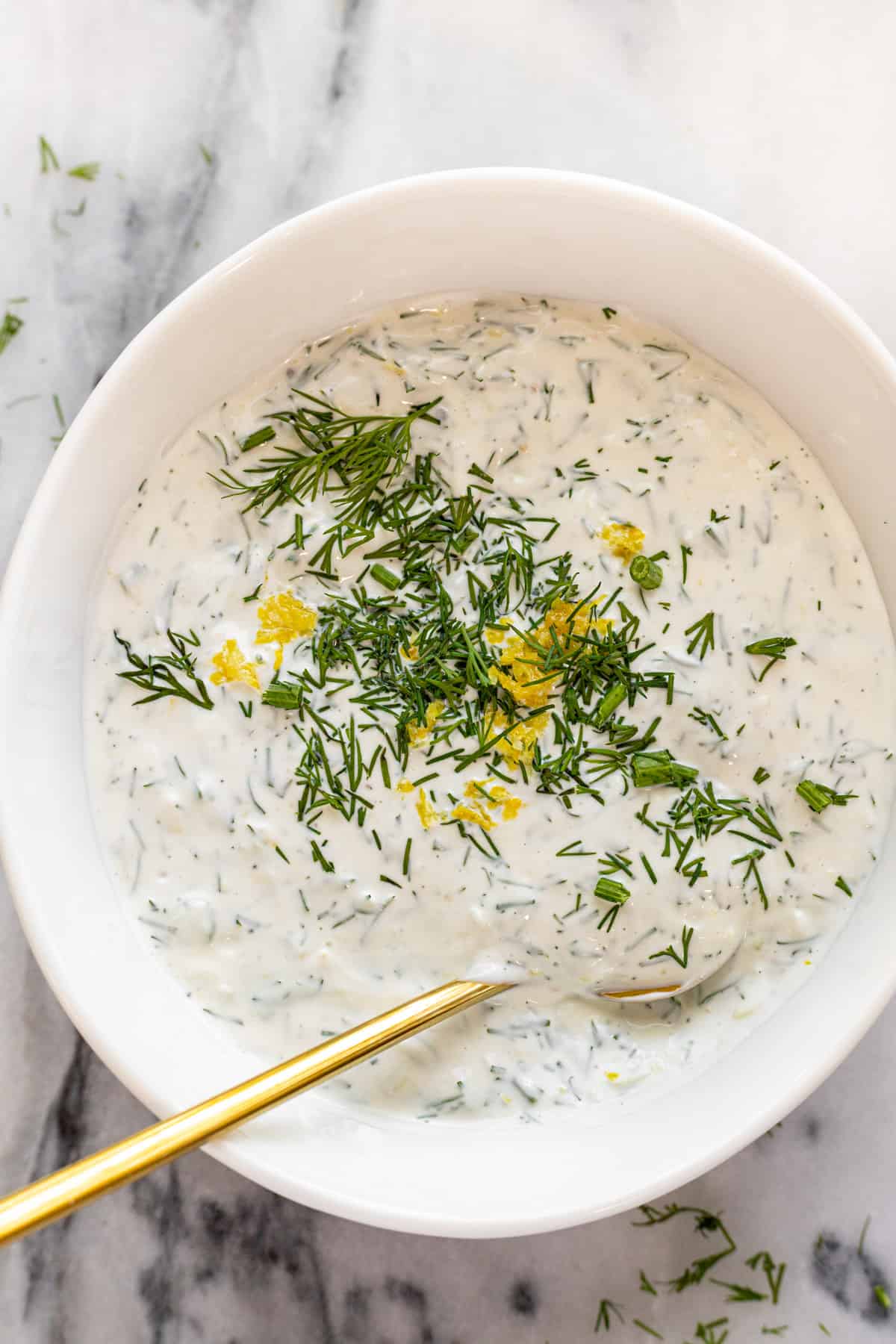 White bowl filled with creamy lemon dill sauce for salmon. 