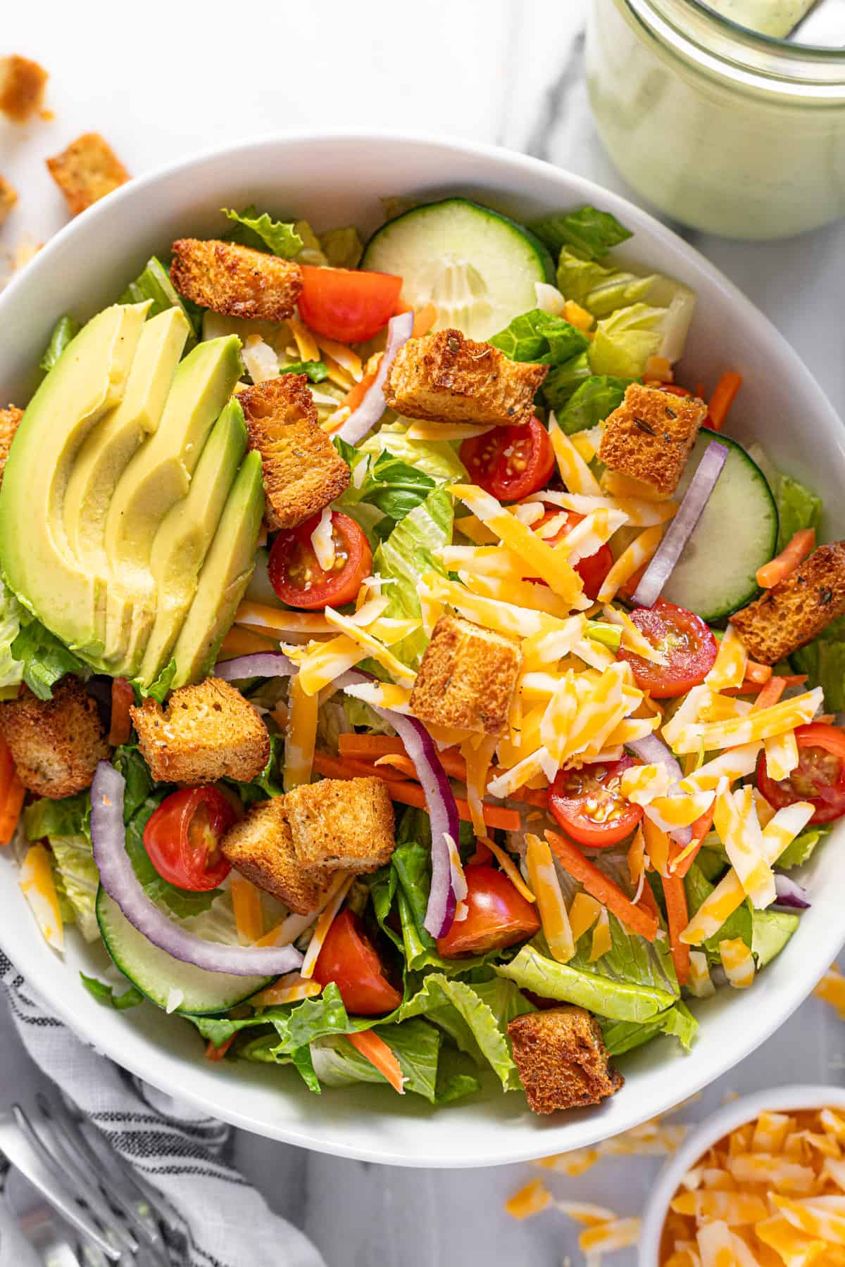 Large bowl filled with house salad filled with veggies, cheese, and croutons.