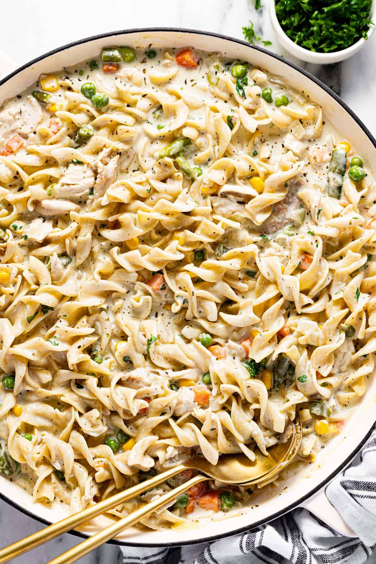 Large saute pan filled with homemade creamy chicken and noodles. 