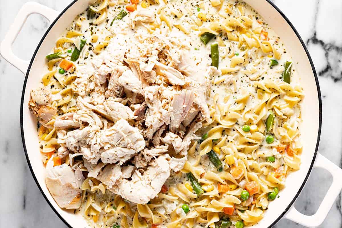 Large saute pan filled with creamy noodles, veggies, and shredded rotisserie chicken. 