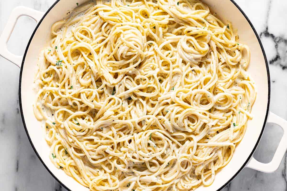 A large pan filled with linguine tossed in cream sauce. 
