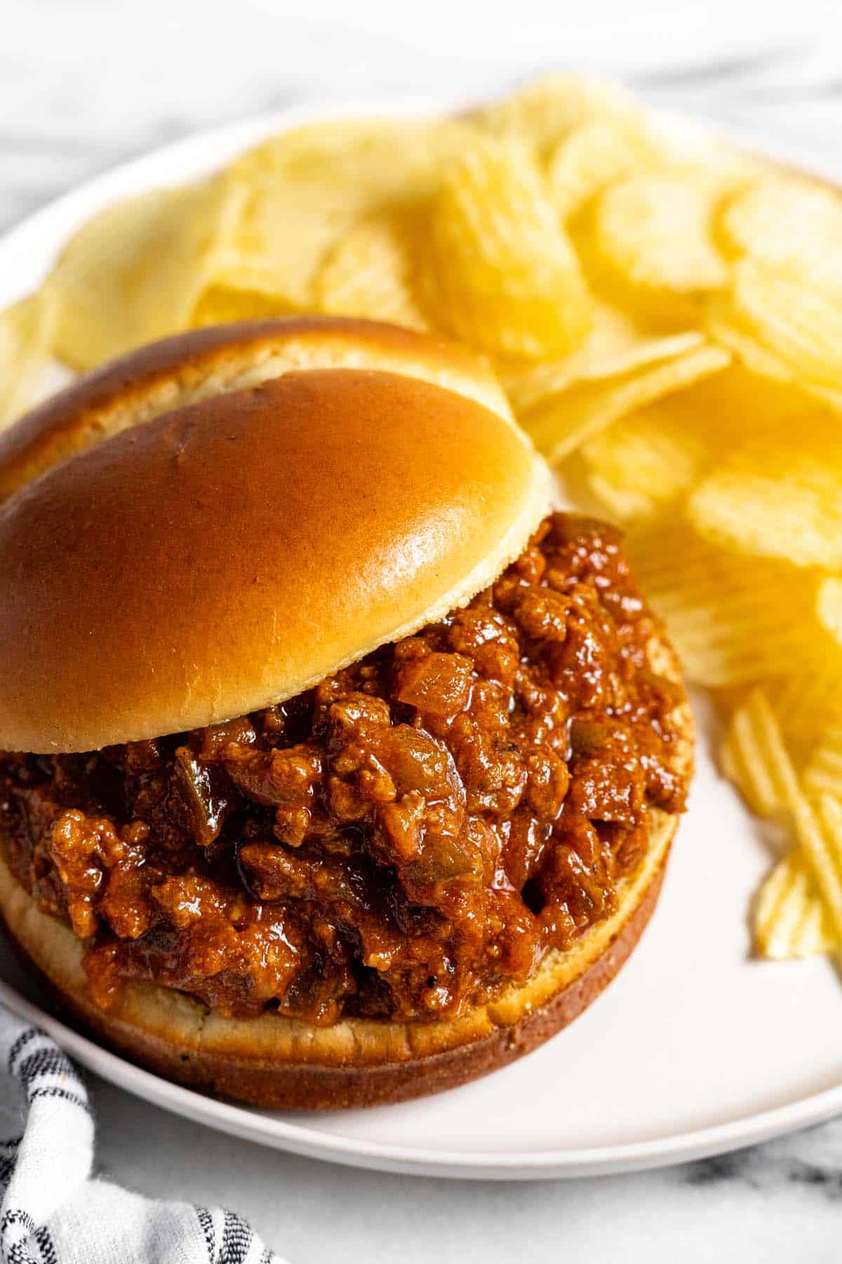 Close up of a sloppy joe on a plate with Ruffles potato chips. 