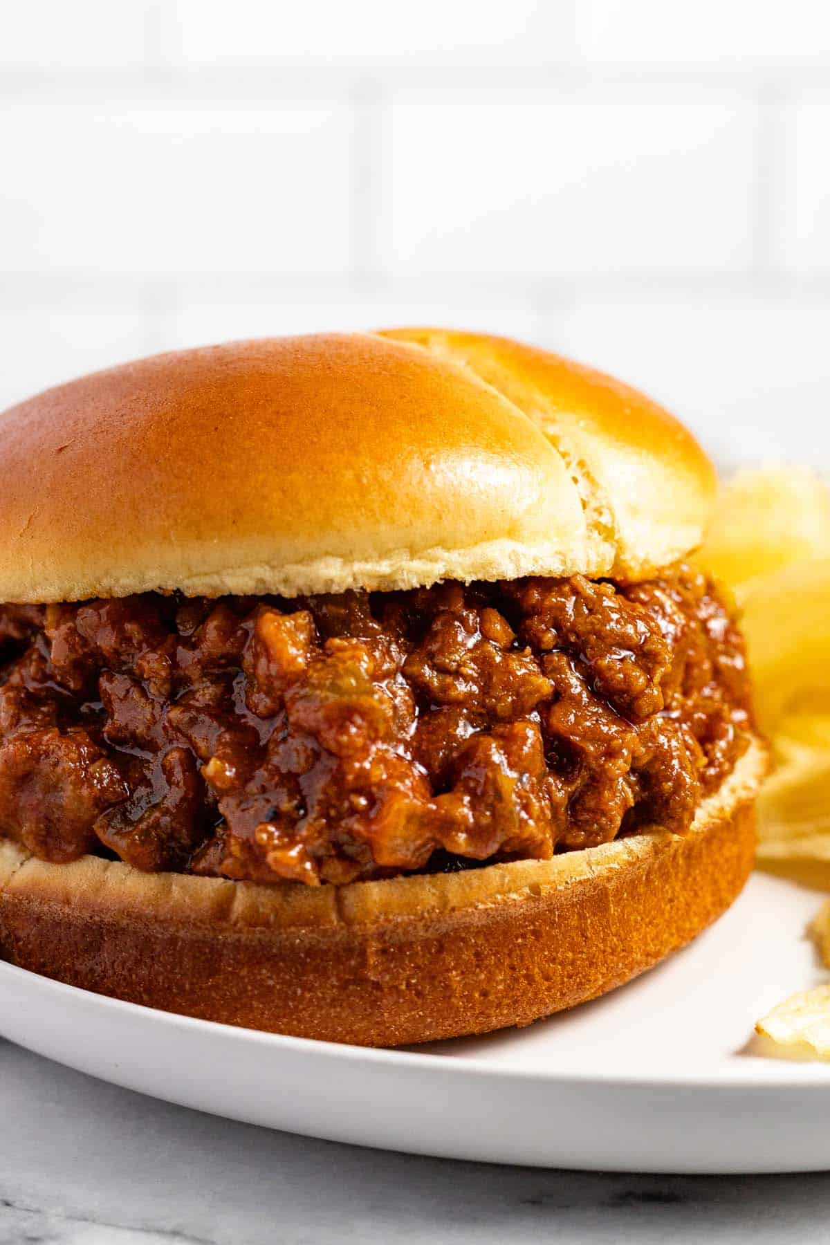 Close up of a sloppy joe on a plate with Ruffles potato chips. 