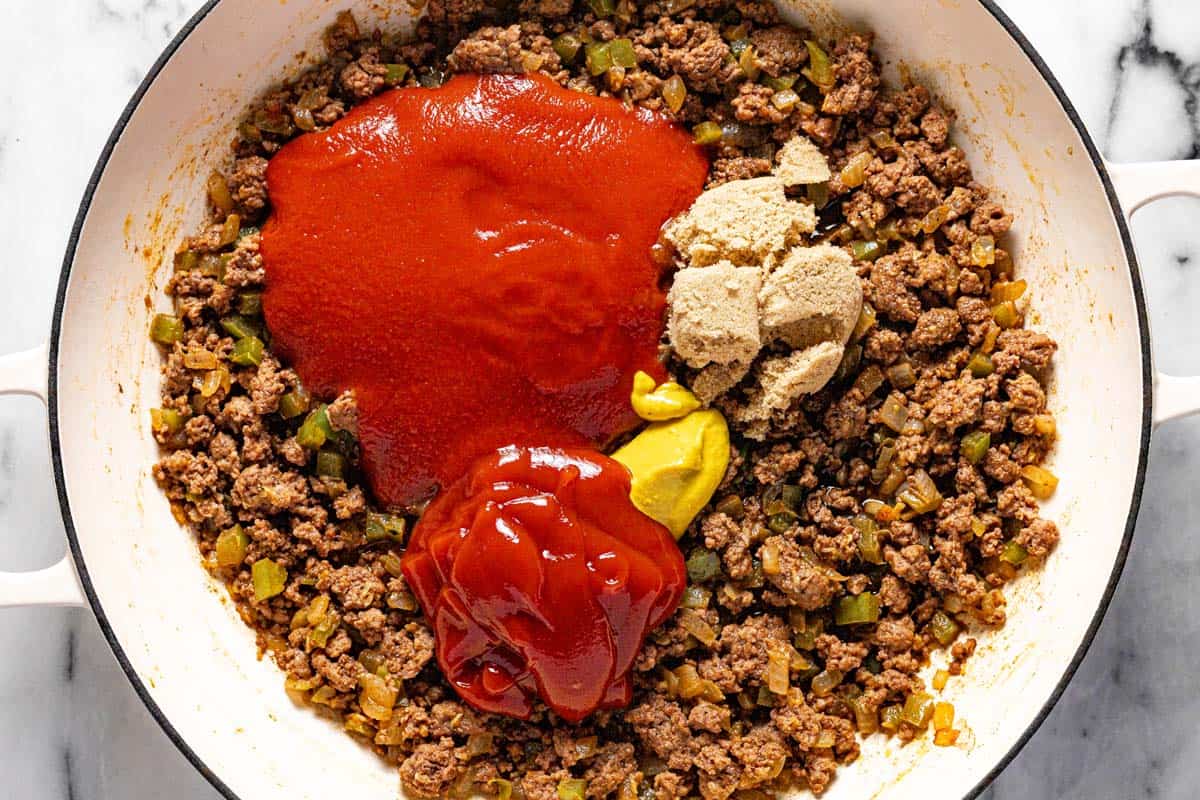 Large pan filled with ground beef, onion, green pepper, tomato sauce, ketchup, mustard, and brown sugar. 