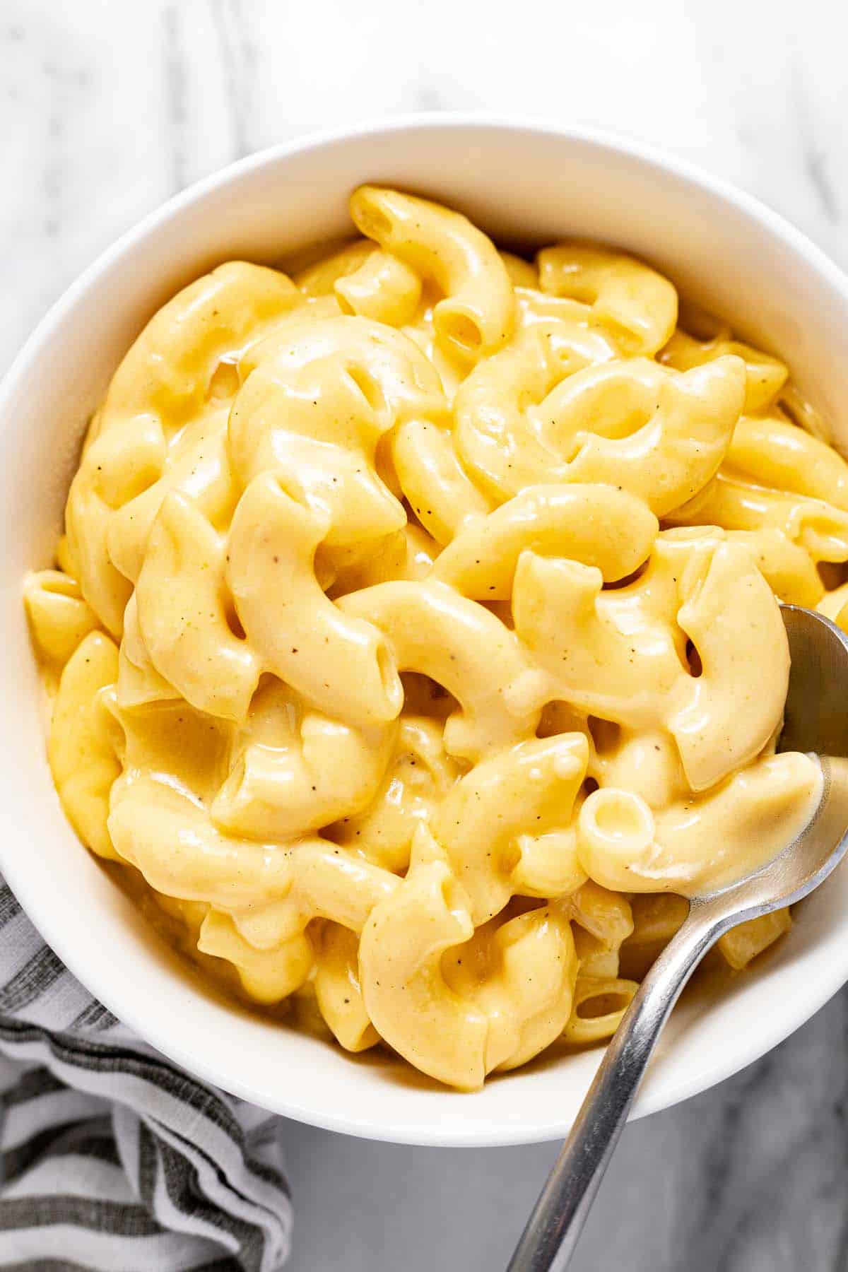 Small bowl filled with creamy slow cooker macaroni and cheese and a spoon. 