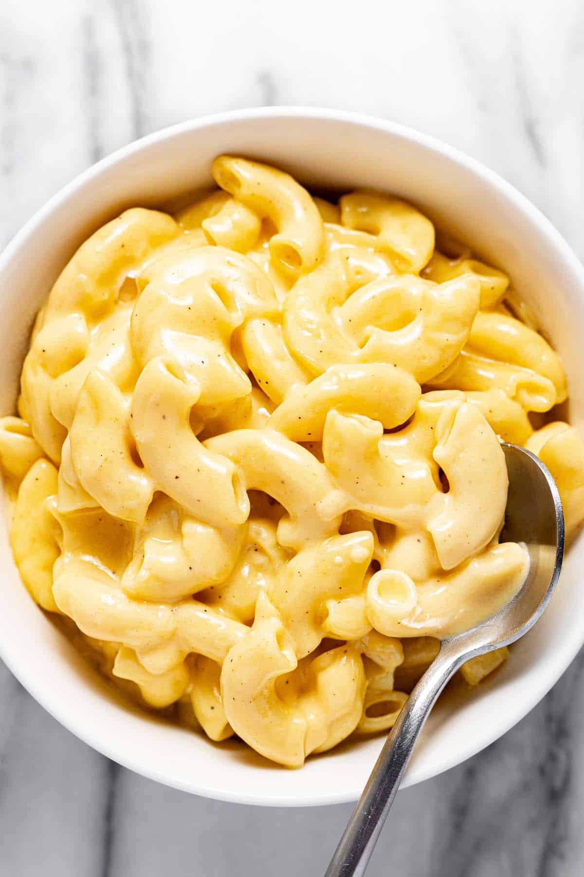 Small bowl filled with super creamy slow cooker macaroni and cheese. 