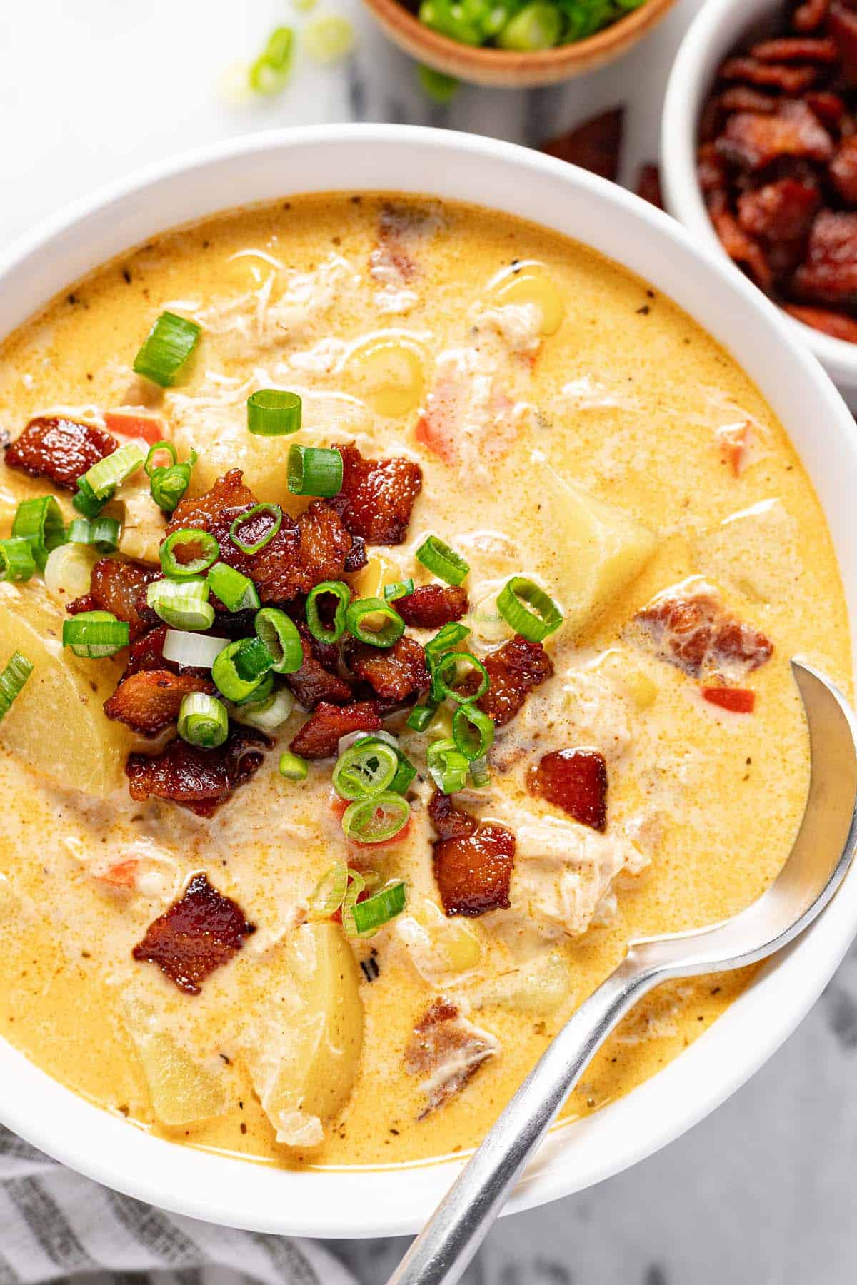 Bowl of chicken corn chowder garnished with bacon and green onion.