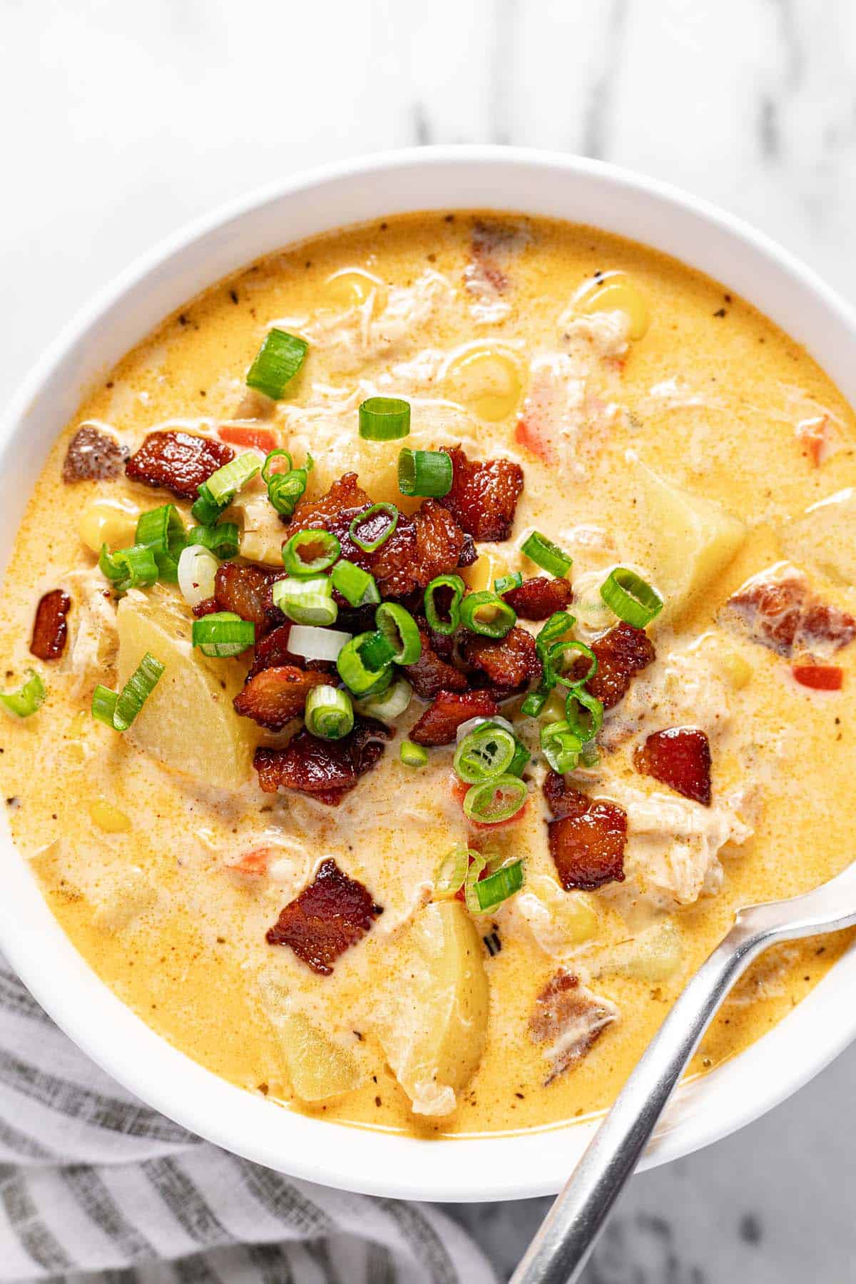 Bowl of chicken corn chowder garnished with bacon and green onion.