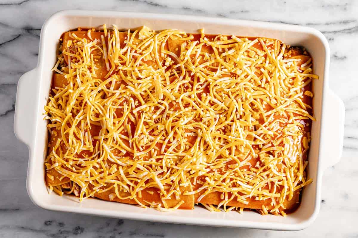 Ingredients layered in a large casserole dish to make chicken enchilada casserole. 