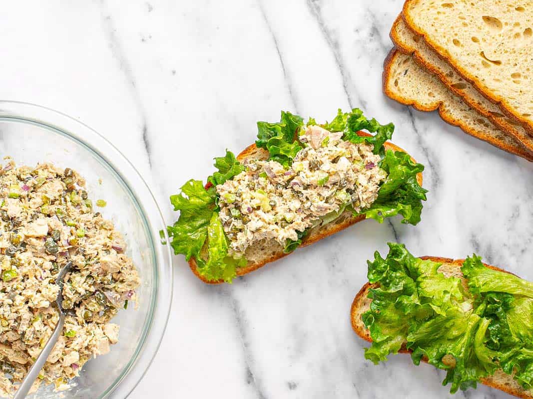 Tuna salad with lettuce on slices of white bread. 
