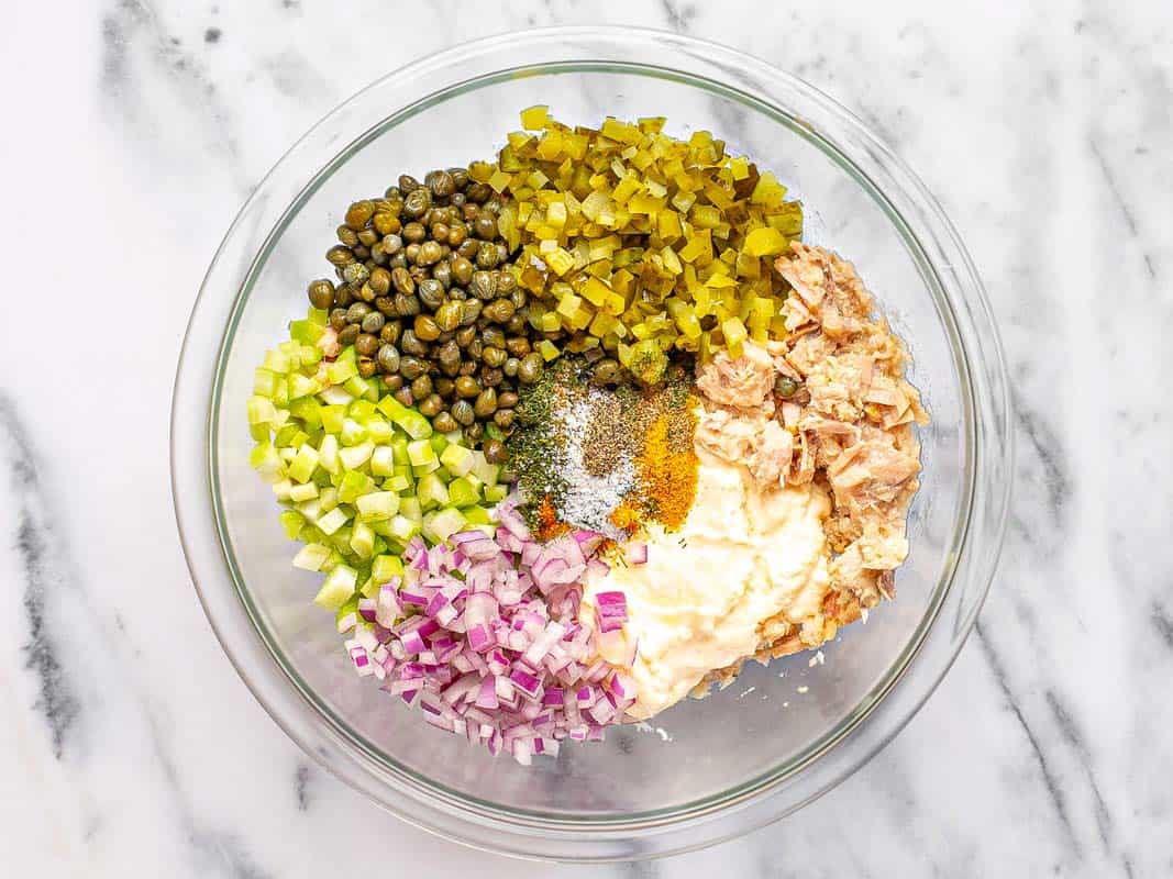 Large bowl filled with ingredients to make tuna salad. 