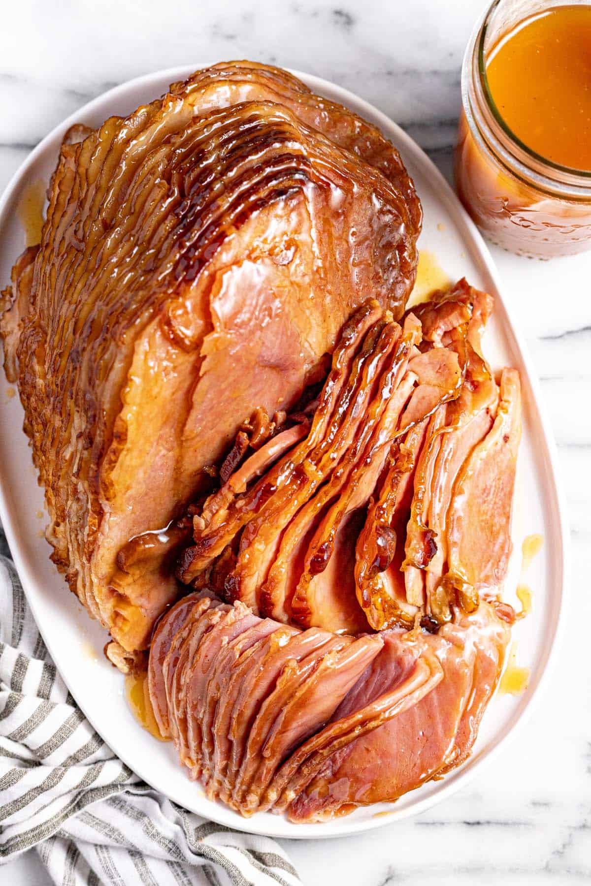 Large spiral cut ham slices brushed with glaze on a large serving platter. 