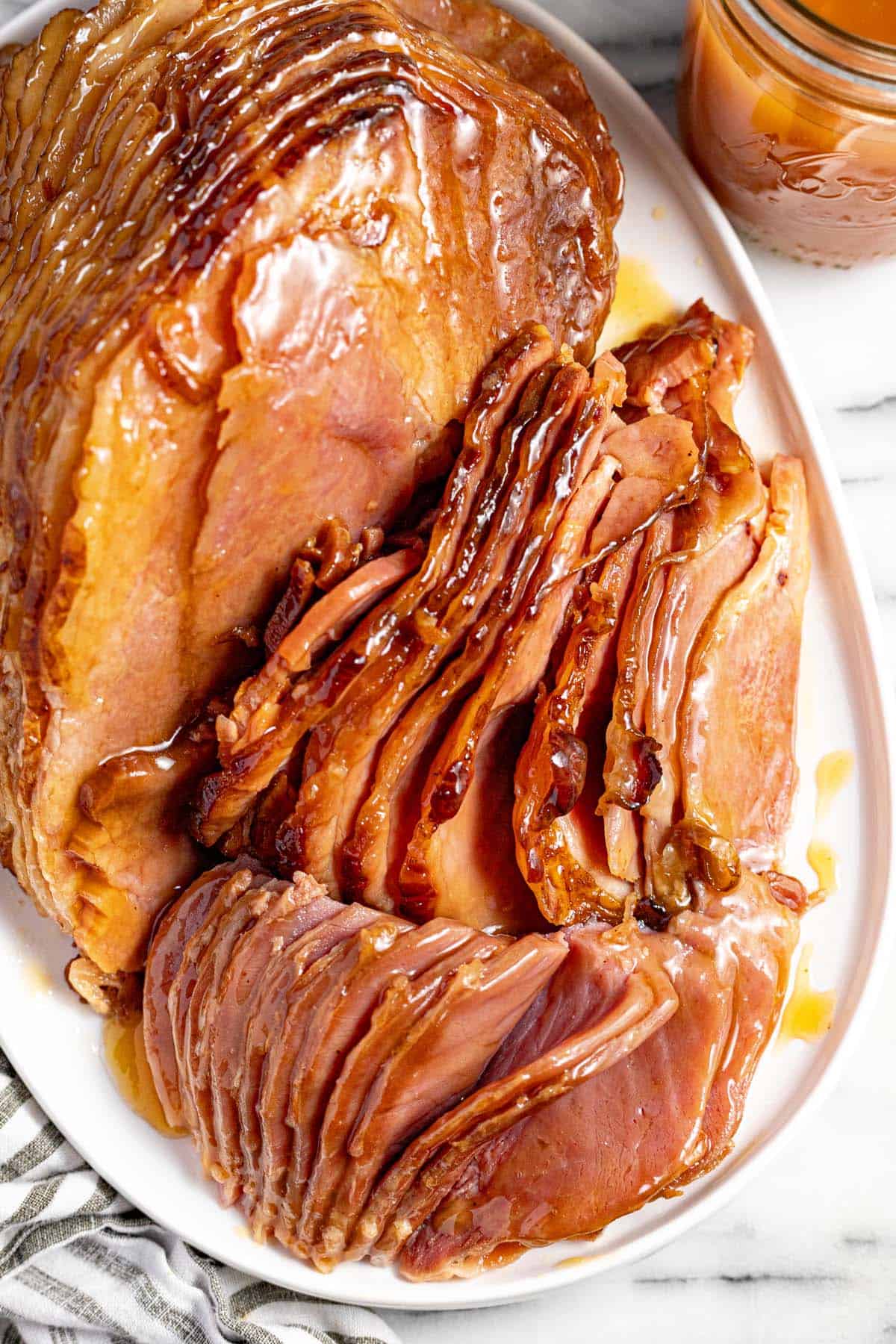 Large spiral cut ham slices brushed with glaze on a large serving platter. 