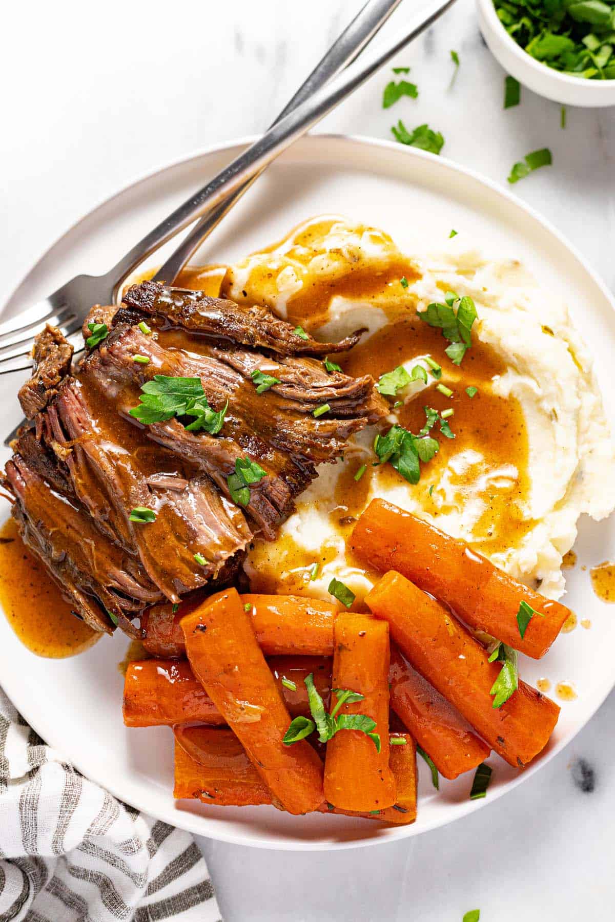Small plate with mashed potatoes, carrots, and slow cooker pot roast. 