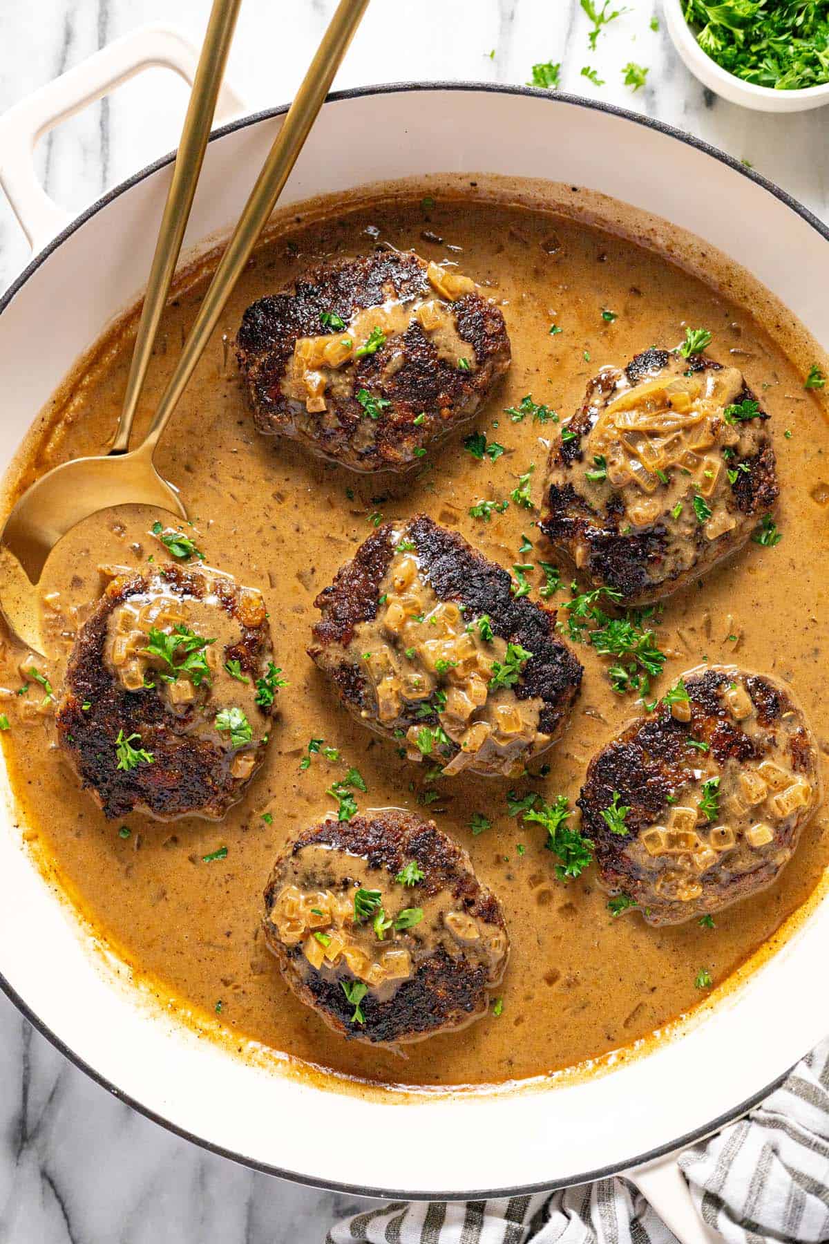 Large pan filled with homemade hamburger steaks in creamy brown gravy. 
