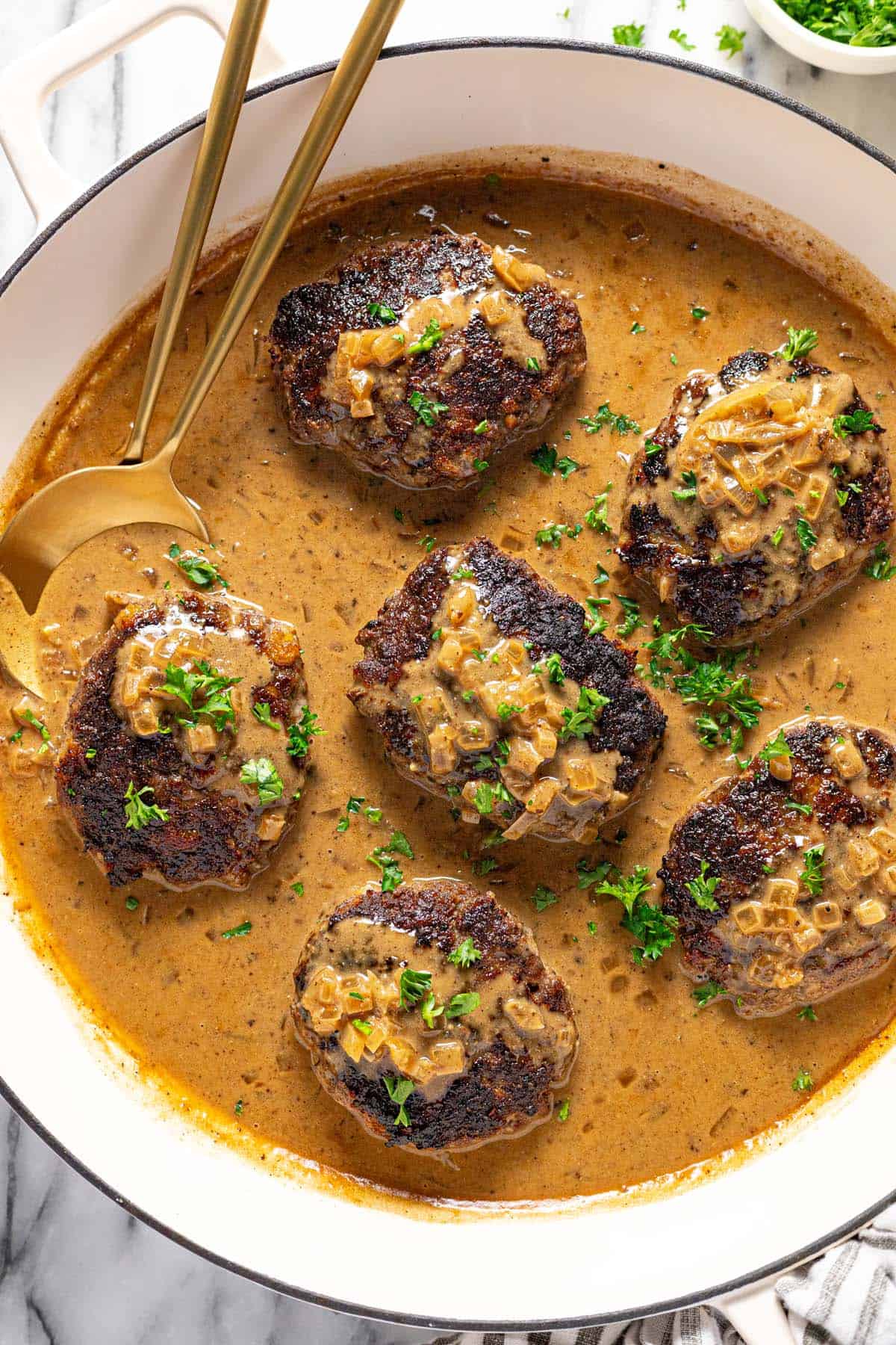Large pan filled with homemade hamburger steaks in creamy brown gravy. 