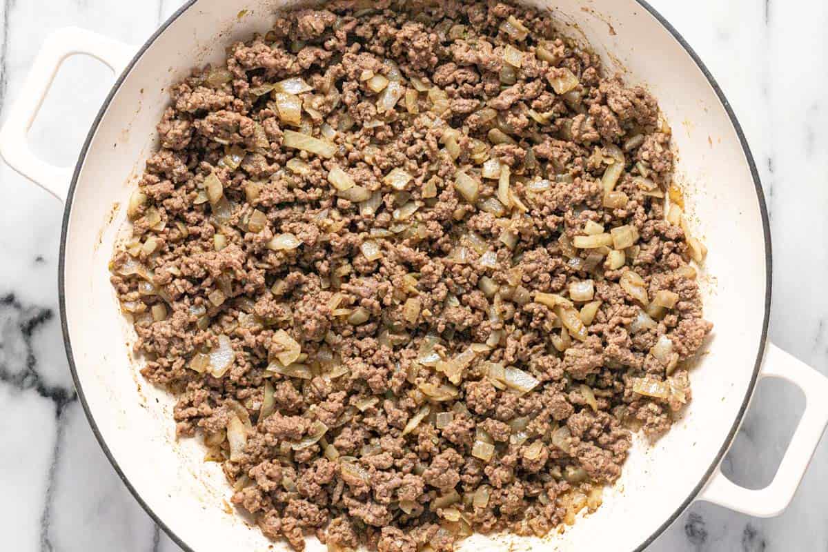 Large pan filled with sauteed veggies and browned ground beef. 