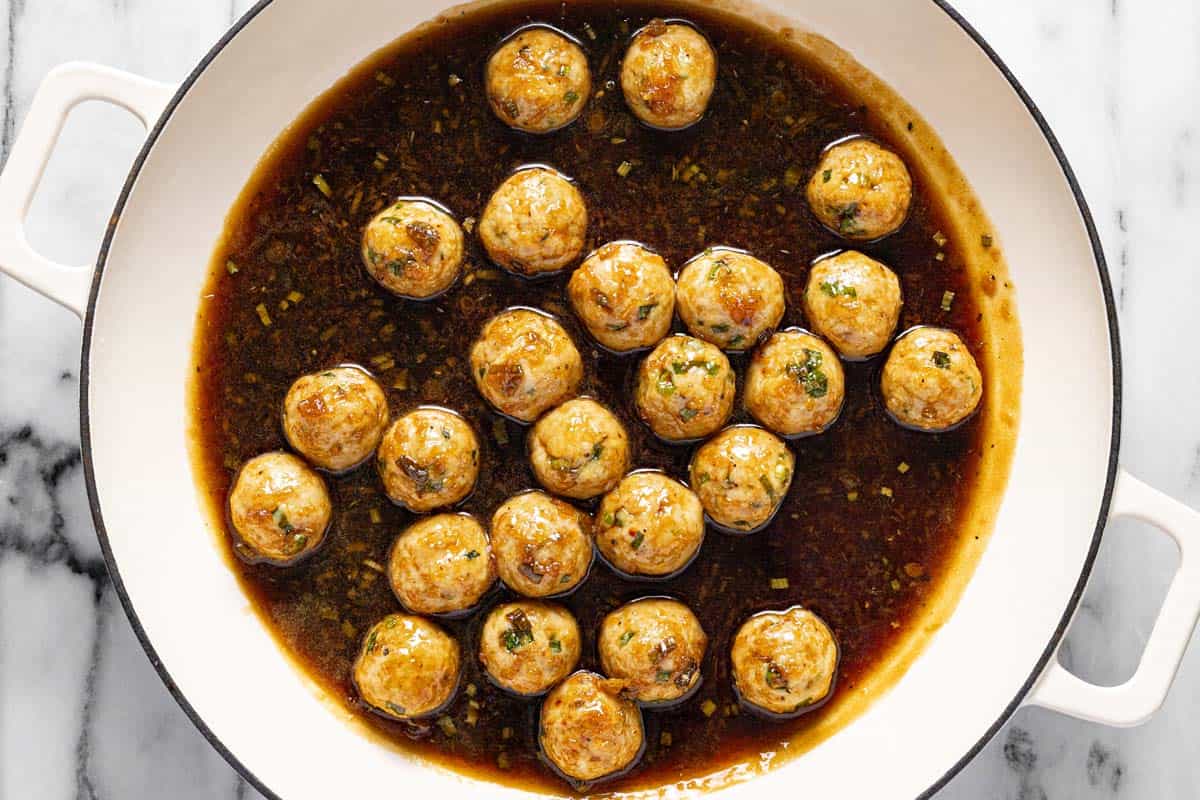 Large saute pan filled with honey garlic baked chicken meatballs in sauce. 