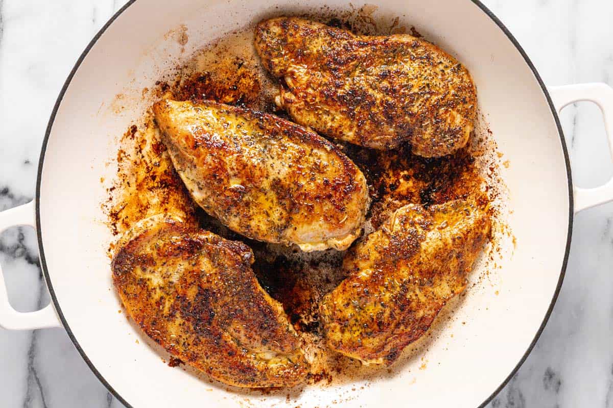 Seasoned chicken breast sauteed in a large round pan. 