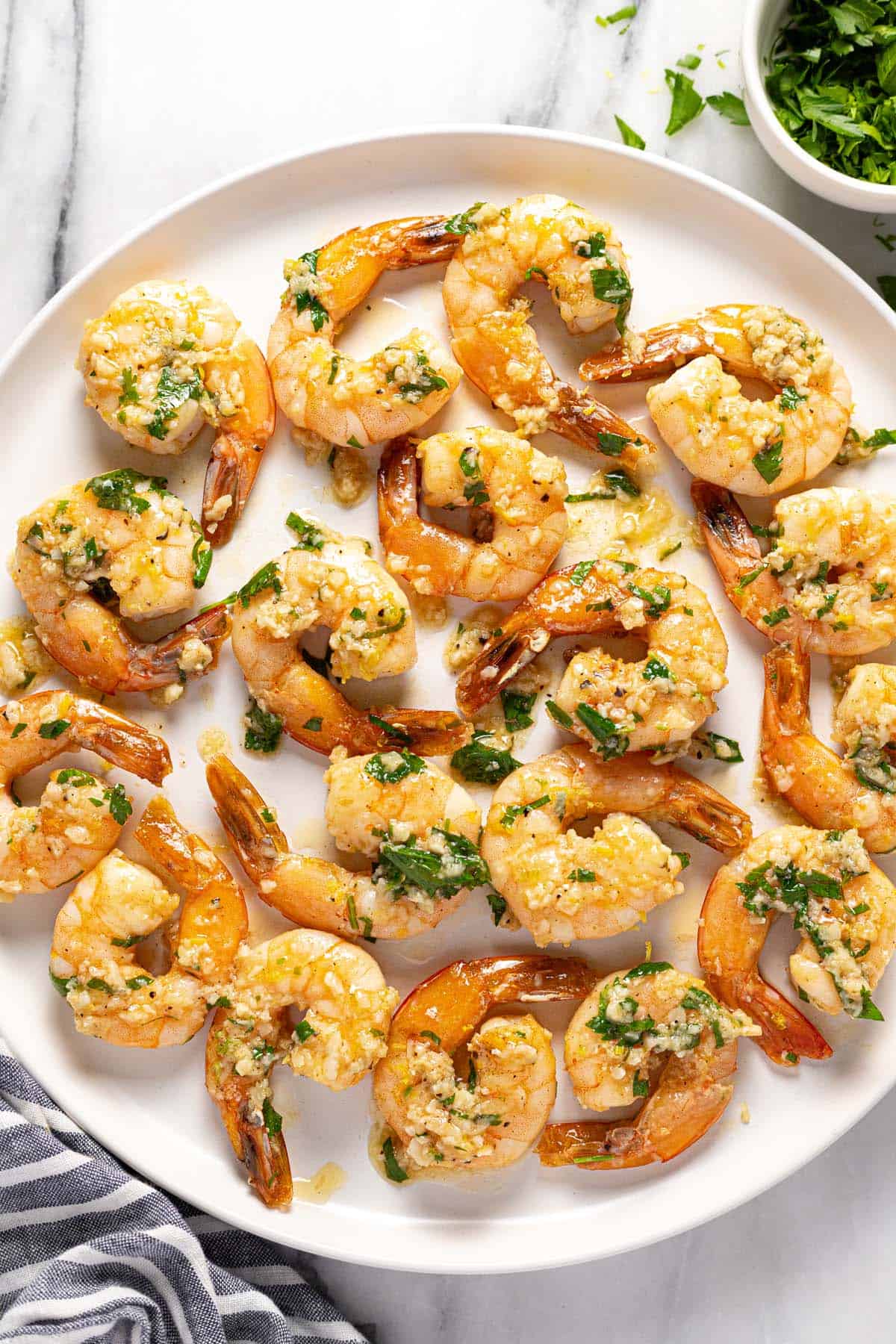 Large round plate filled with garlic butter shrimp. 