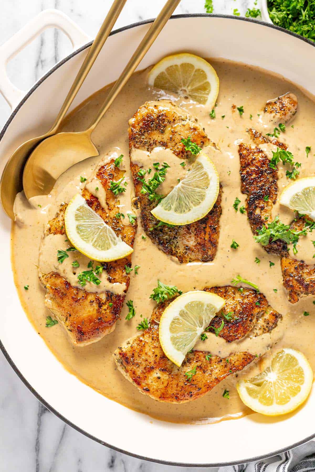 Large pan filled with sauteed lemon chicken with creamy sauce. 