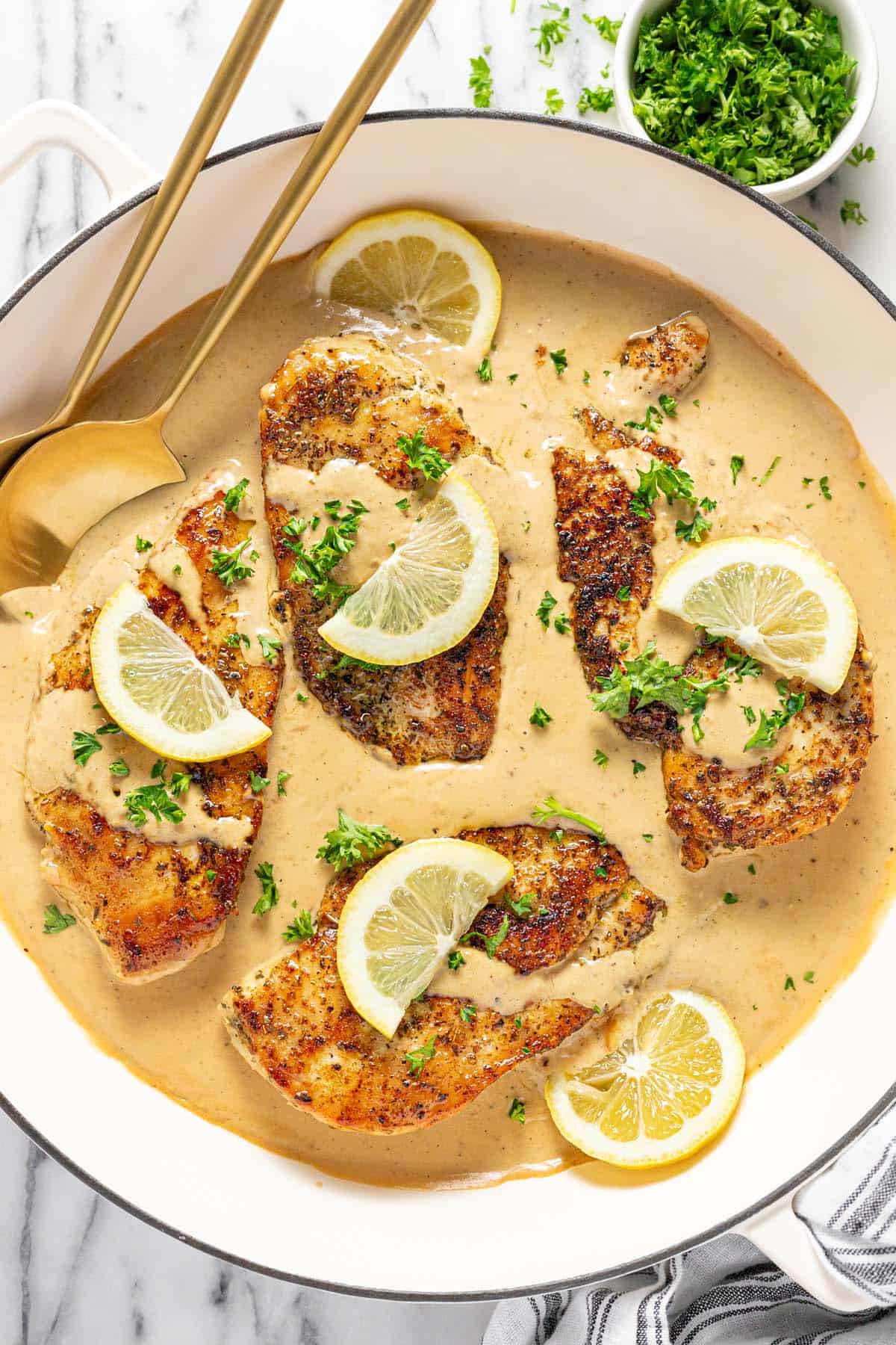 Large pan filled with sauteed lemon chicken with creamy sauce. 