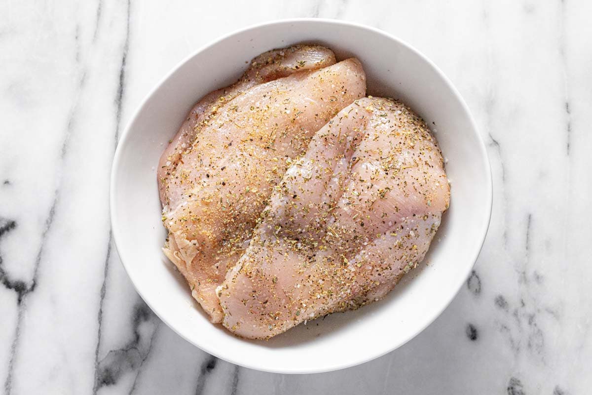 Bowl of chicken breast seasoned with herbs and spices. 