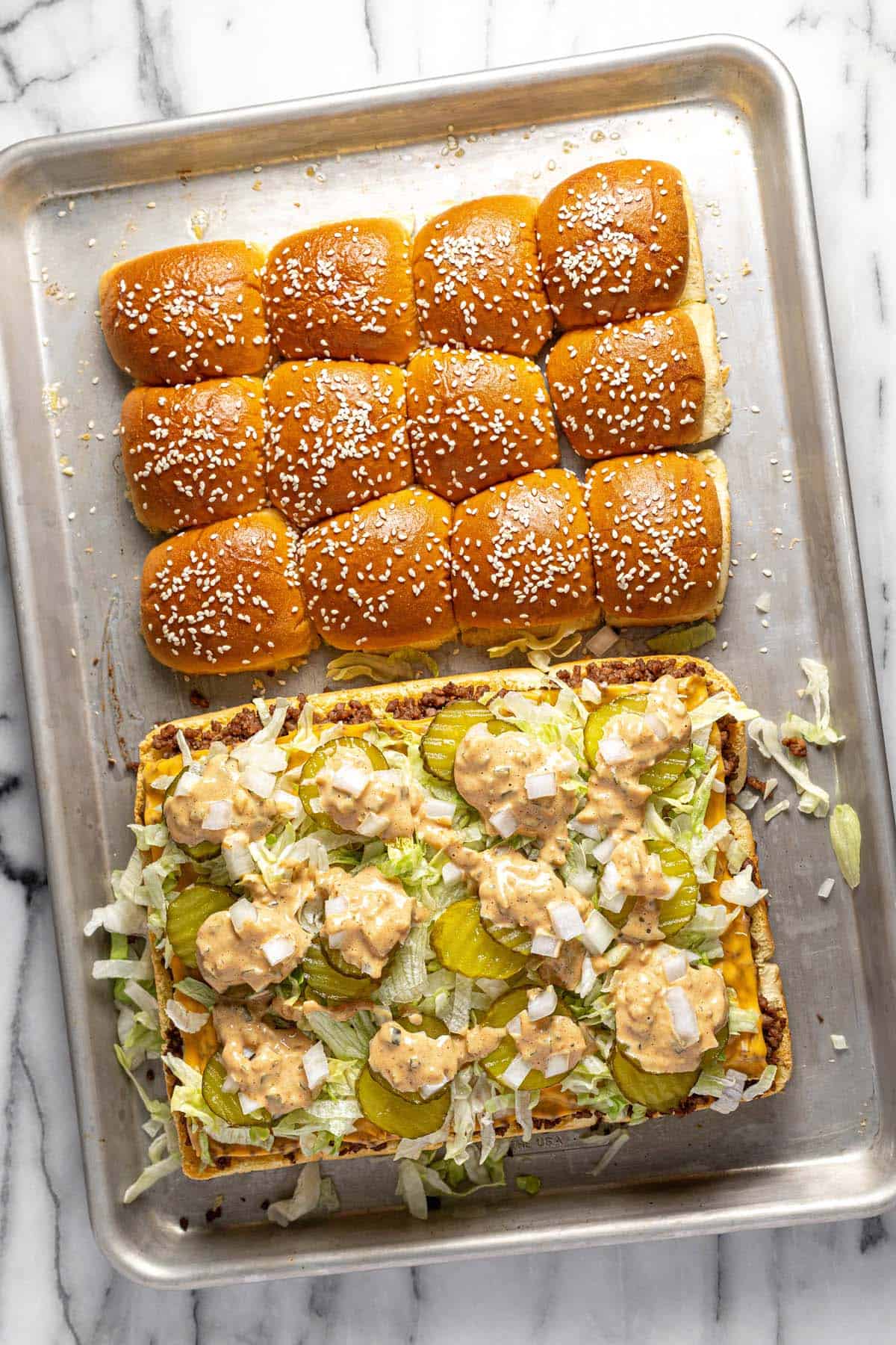 Big Mac sliders fresh from the oven topped with lettuce, pickles, and burger sauce. 