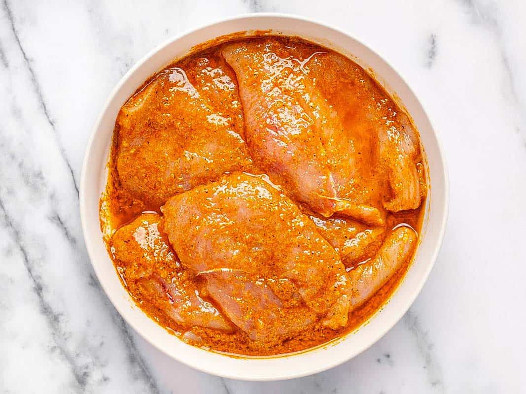 Chicken breast marinating in a large bowl. 