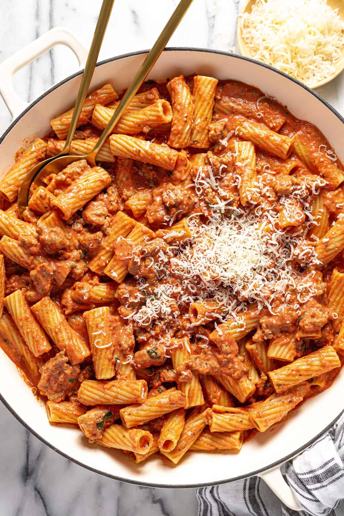 Large pan of creamy Italian sausage pasta with shredded Parmesan cheese. 