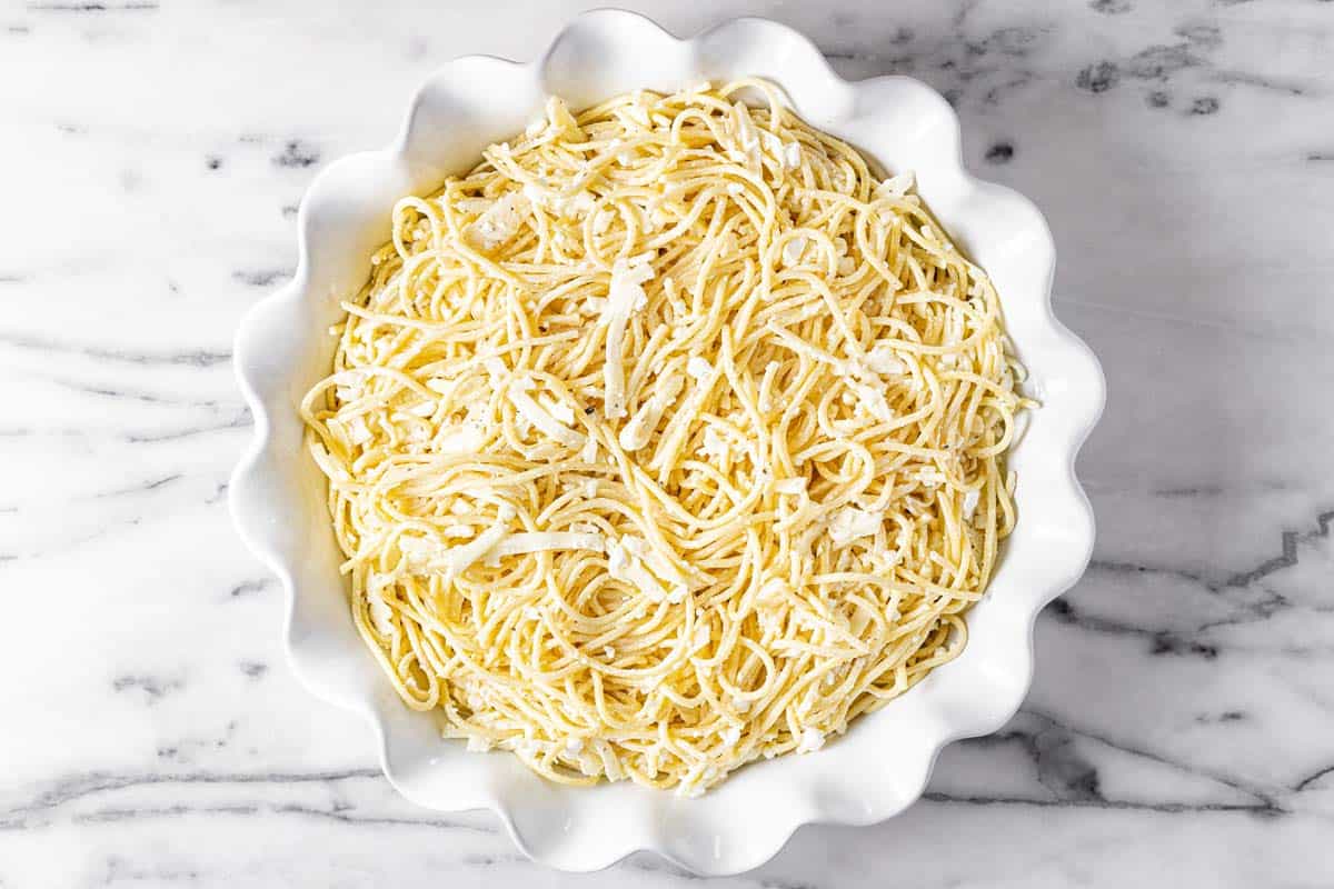Large pie pan filled with cheesy spaghetti. 