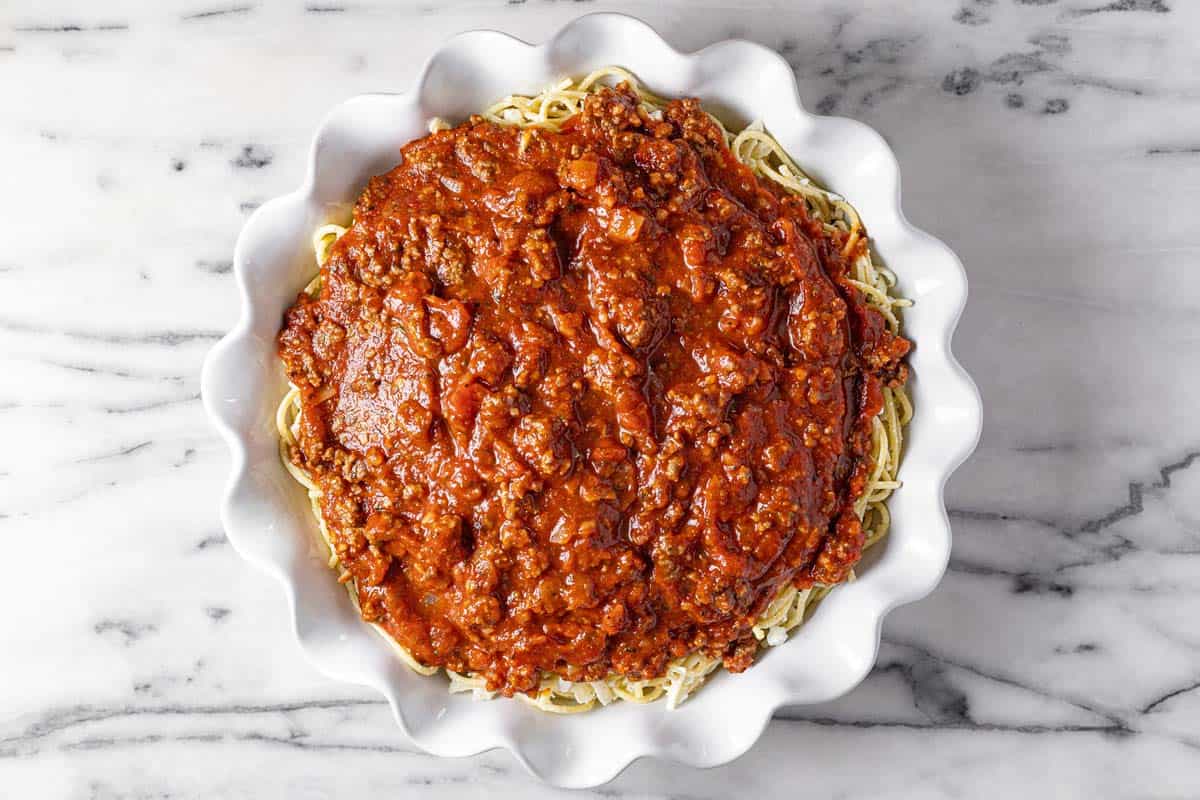 Large pie pan filled with spaghetti and meat sauce. 