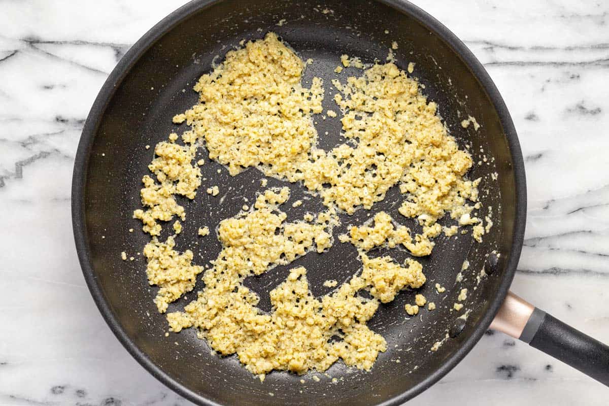 Large saute pan filled with a roux mixture and minced garlic. 