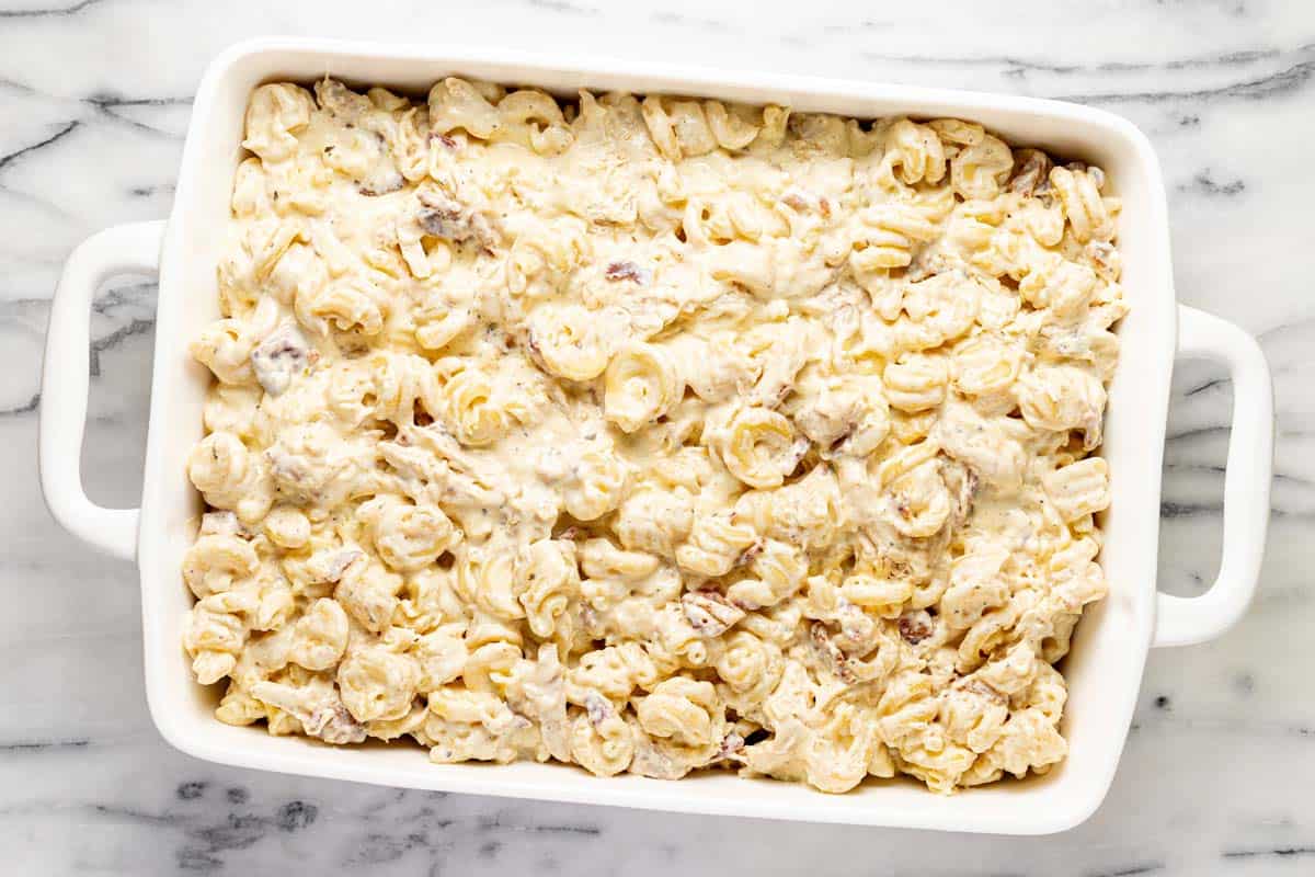 Creamy pasta, chicken, and bacon in a large baking dish. 