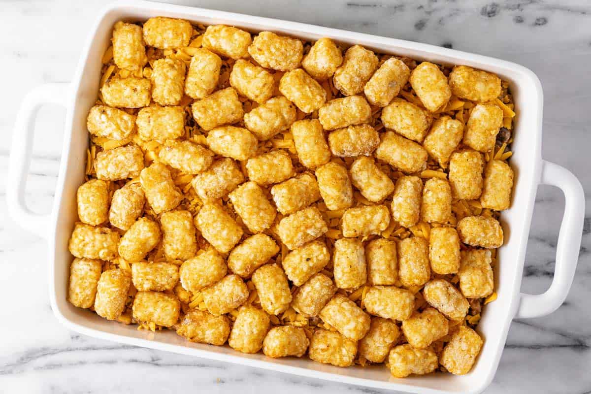Large white baking dish filled with cowboy casserole topped with tater tots. 