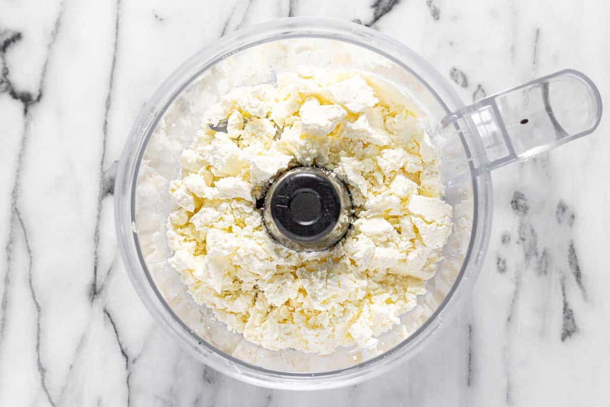 Food processor with ingredients to make creamy feta dip. 