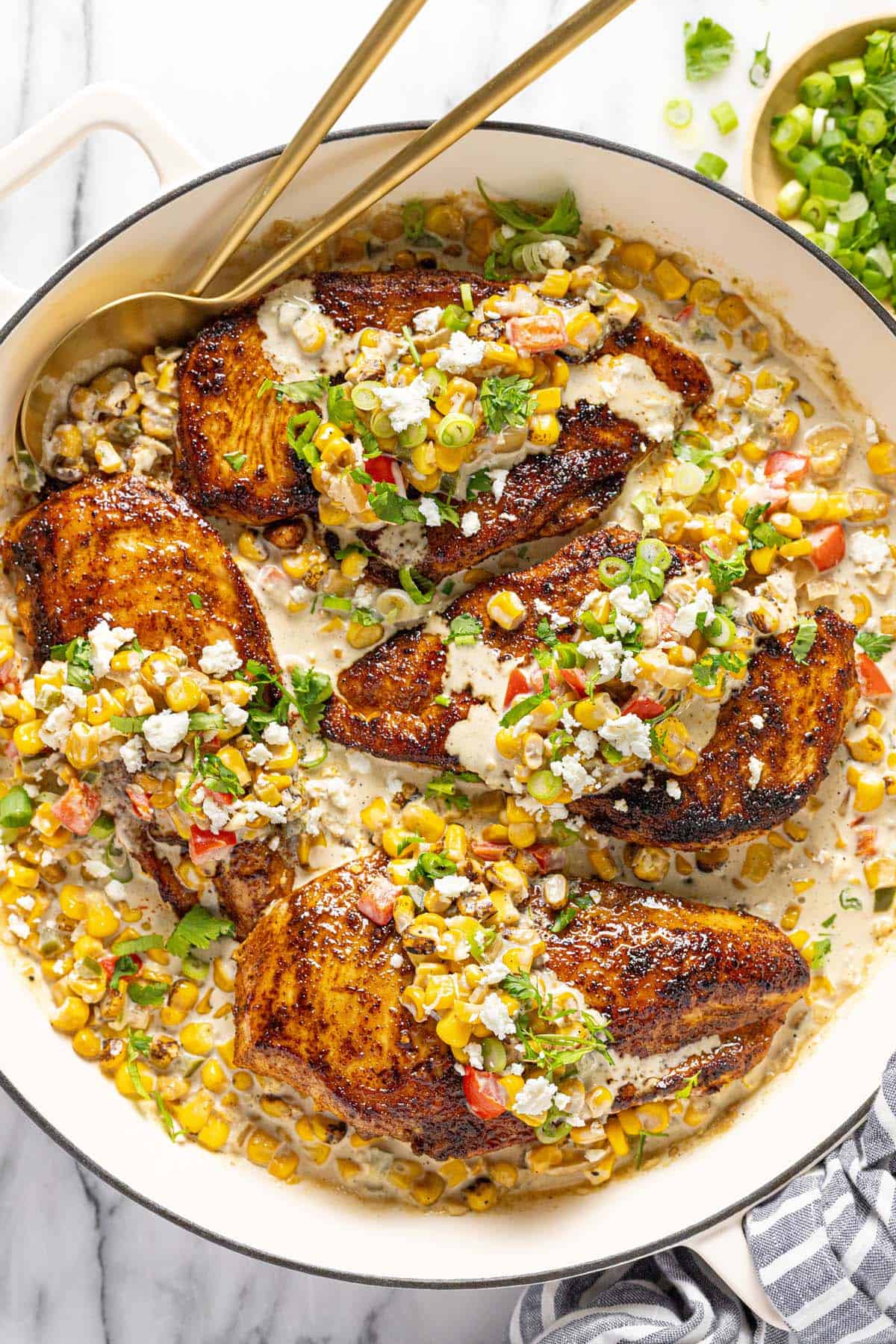 Large skillet with street corn chicken garnished with green onion and cilantro. 