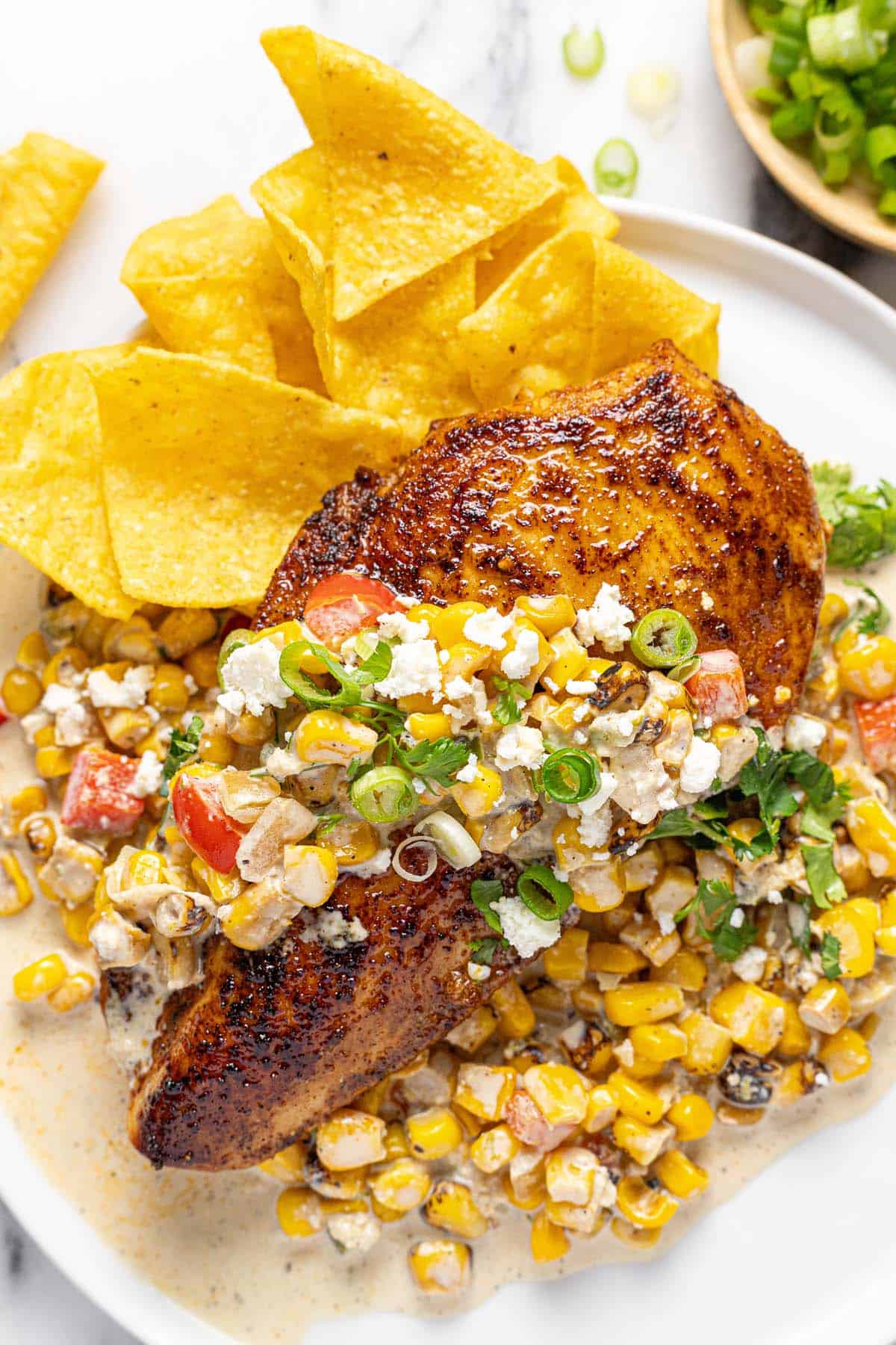 Plate with sauteed street corn chicken and tortilla chips. 