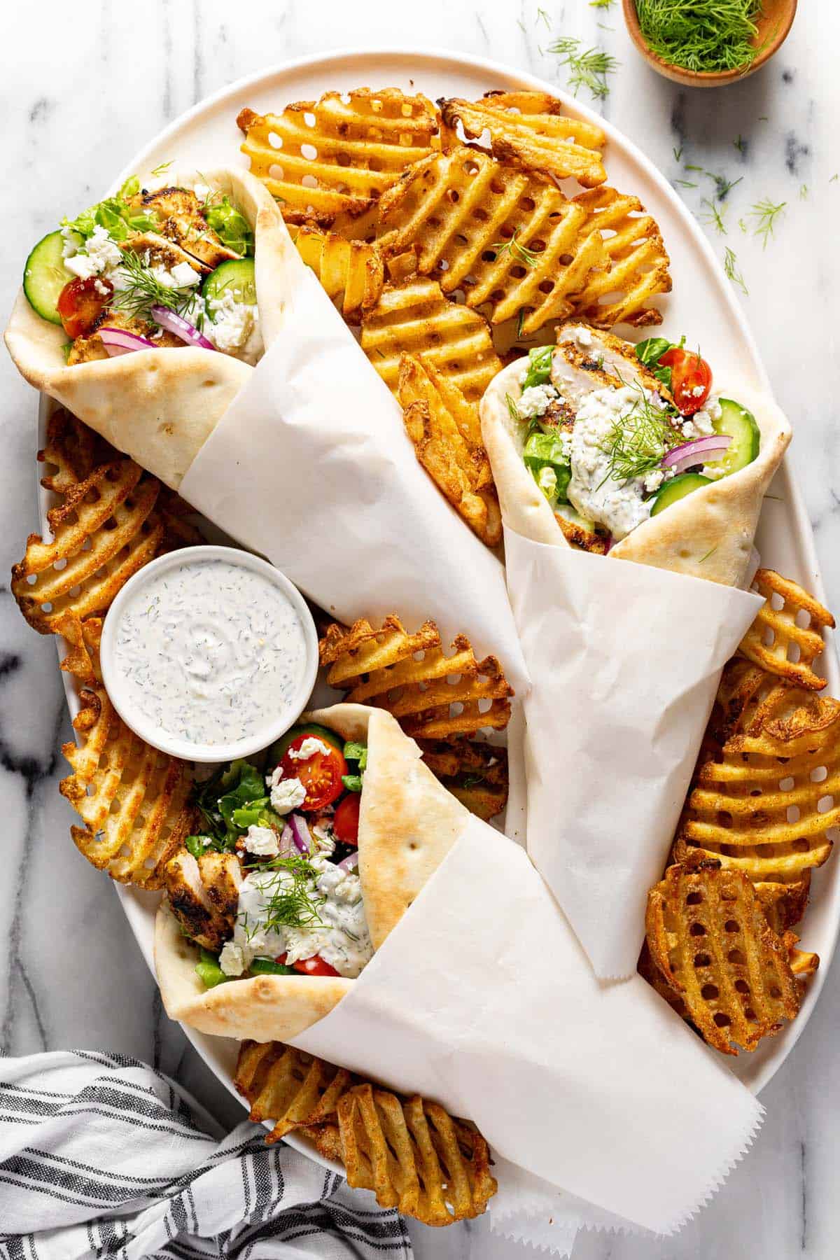 Large platter filled with Greek chicken gyros and waffle fries. 