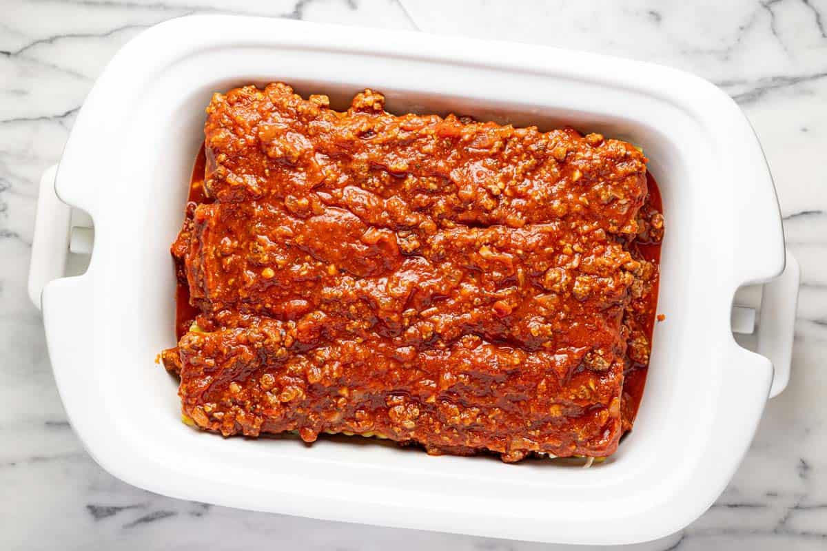 Layers of lasagna in a rectangle slow cooker. 