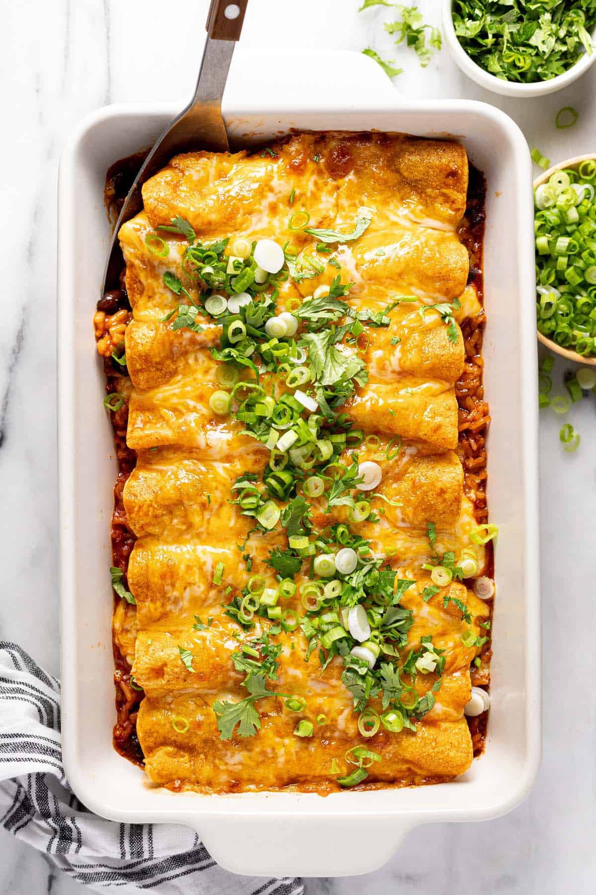 Large pan filled with Spanish rice and ground beef enchiladas. 