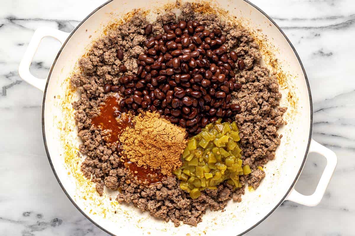 Large pan filled with ground beef, green chilies, taco seasoning, and enchilada sauce. 