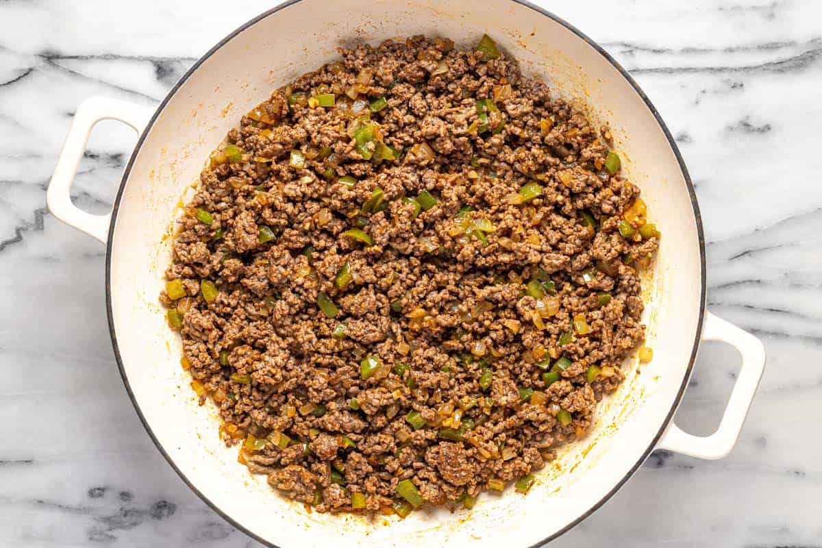 Large sauté pan with ground beef and sauteed veggies. 