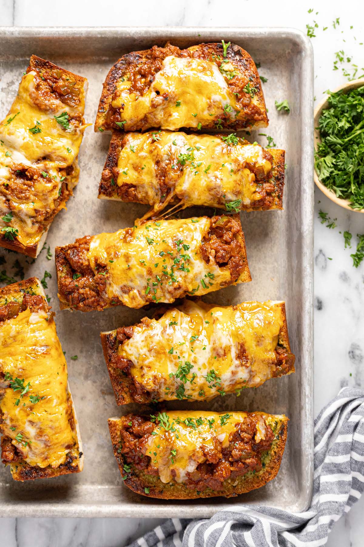 Metal pan with sliced sloppy joe garlic cheese bread on it. 