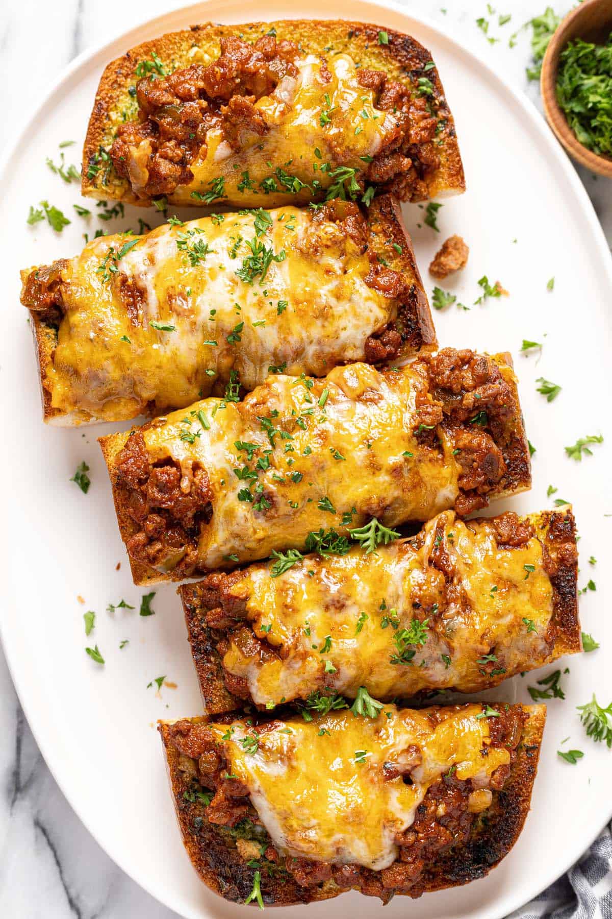 Sloppy joe garlic cheese bread sliced into pieces on an oval platter. 