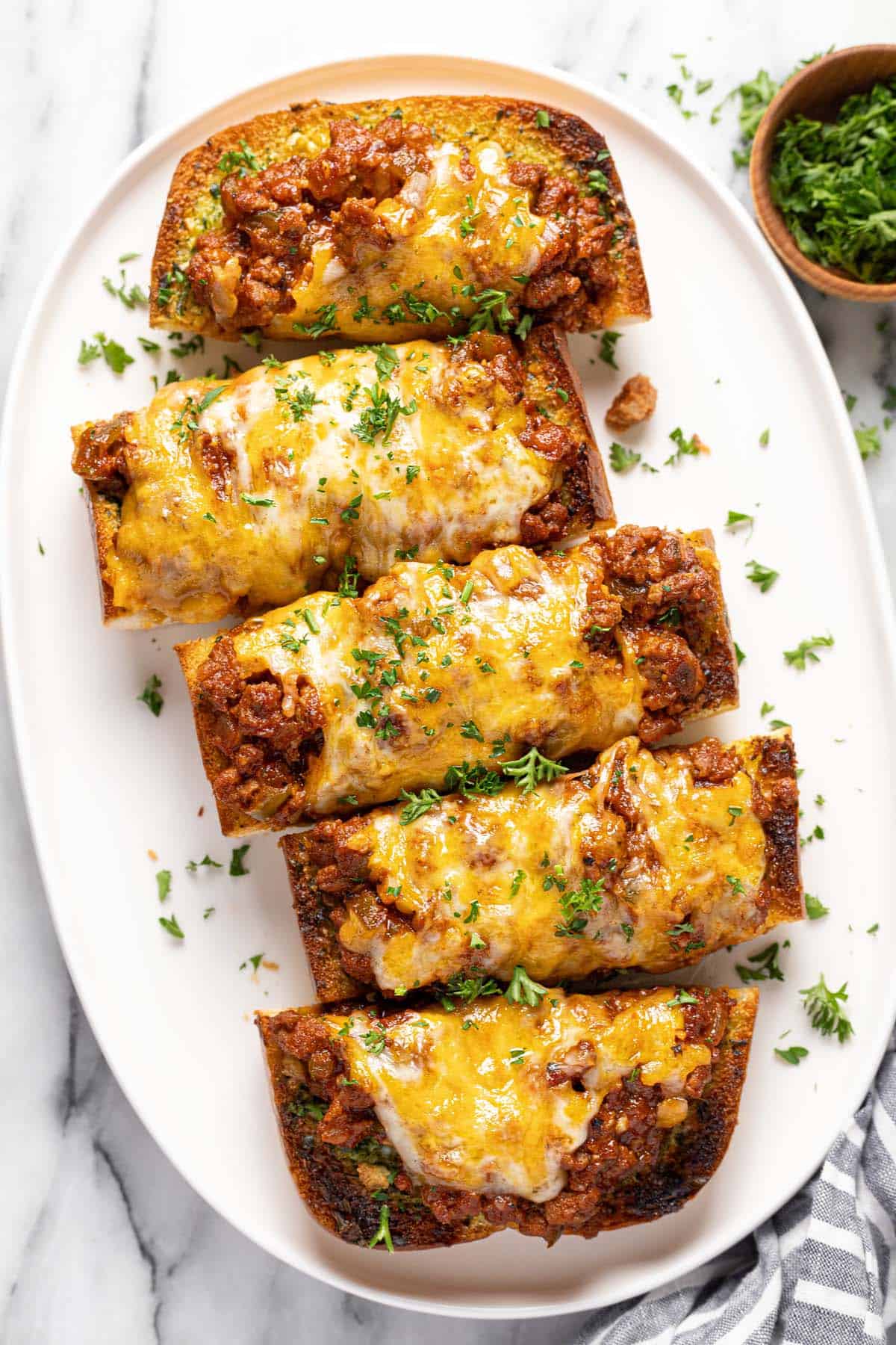 Sloppy joe garlic cheese bread sliced into pieces on an oval platter. 